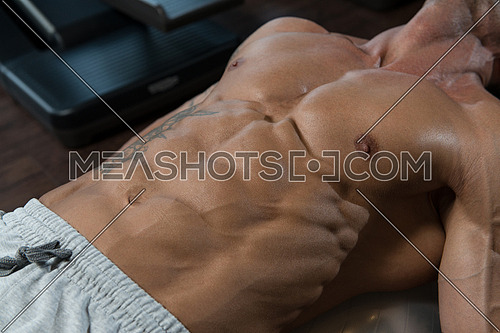 Muscular Mature Man Exercising Abdominals On Exercise Ball In Modern Fitness Center