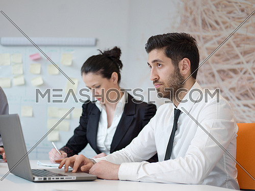 portrait of young modern arab business man with beard at office,   group of  business people  on meeting making presentation  in background