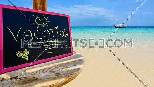 In the picture a Zanzibar beach which is a small blackboard with the words \