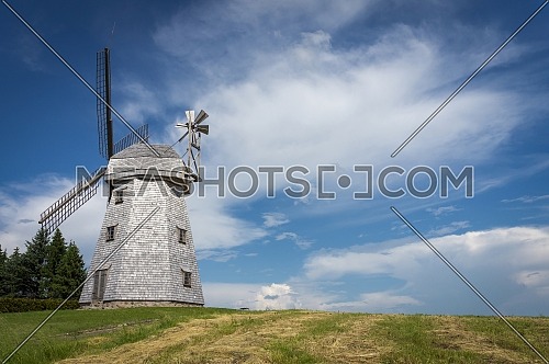 Old windmill in grassland in a country landscape under a cloudy blue sky in a scenic landscape