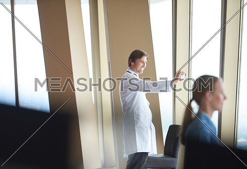 handsome doctor have video call and taking selfie photo on cellphone at modern hospital indoors