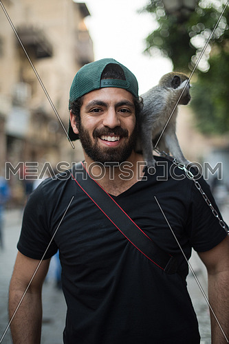 Portrait of a young middle eastern tourists who enjoy with a monkey on his shoulder