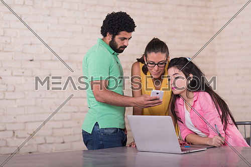 informal group of young middle eastern businessmen having a meeting while using a laptop in a modern office