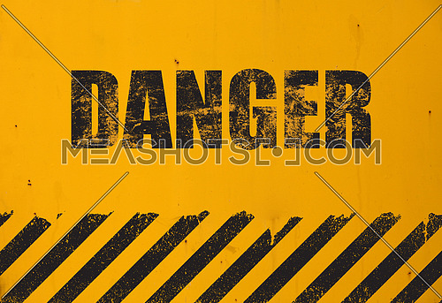 Old yellow weathered painted background with grunge black danger sign and stripes