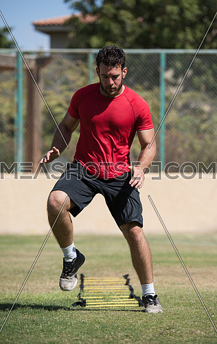 young middle eastern man athlete running and exercise to speed ladder out in the field on a sunny day