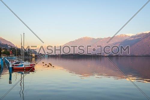 Colorful red boats on stunning mountain lake in Alps during sunset,panorama of Iseo lake from the city of Lovere,Bergamo,Lombardy Italy.