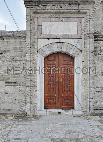 Wooden aged vaulted engraved door and exterior stone wall, Suleymaniye Mosque, Istanbul, Turkey