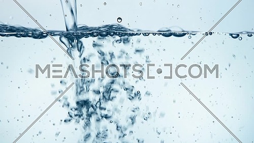 Pouring pure clear cold water in transparent glass jar or teapot until full, close up, low angle side view, slow motion
