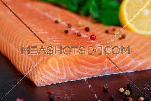 Healthy fresh salmon on the black cutting board piece of salmon with ingredients on marble