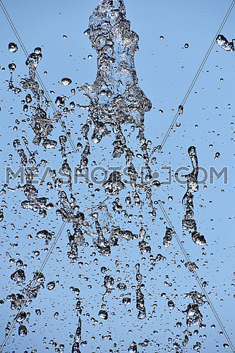 Close up water drops of fountain stream splash over background of clear blue sky
