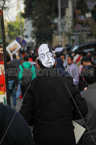 A man from his back wearing ahmed harara mask in a protest