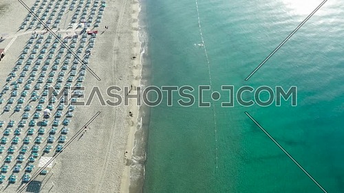 Aerial view of beautiful sea and beach with parasol at sunny day, seascape and hill mountain on backgrond, Simeri Mare, Calabria, Southern Italy