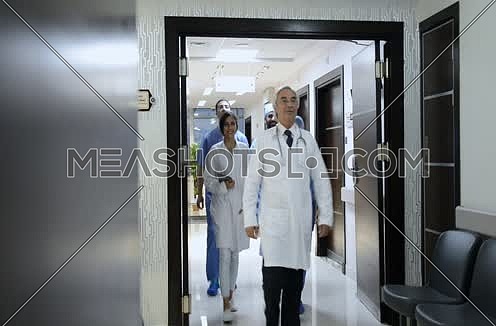middle eastern doctor and his team walking forward in hospital corridor