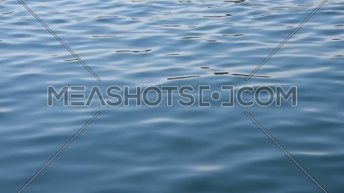 Close up background of blue sea waves and ripples running on water surface