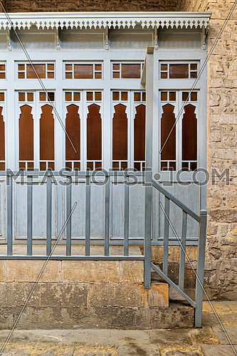 Array of wooden blue doors with yellow glass over stone wall, wooden blue balustrade, and stone stairs at historical traditional bathhouse (Hamam Inal), Cairo, Egypt