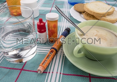 Medication during breakfast, injector of insulin together with a bottle of pills, conceptual image, composition horizontal