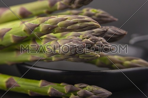 Skillet with fresh raw green spring asparagus spears ready for cooking over a black background with copy space