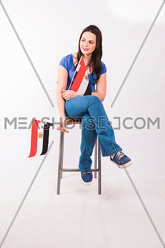 young lady cheering and sitting on a metal chair and holding small egyptian flag