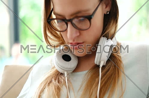 Young Woman Listening To Music On Cellphone Sitting On Armchair At Home