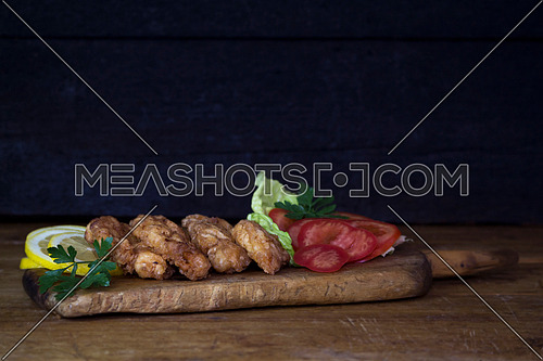 Breaded Chicken Meat With Salad And Lemon Resting On a Rustic Wooden Board