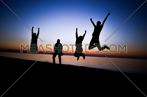 four friends jumping at the beach during sunset magical hour