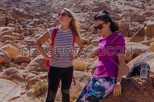 Long shot for two female tourists exploring at Sinai Mountain for wadi Freij by day.