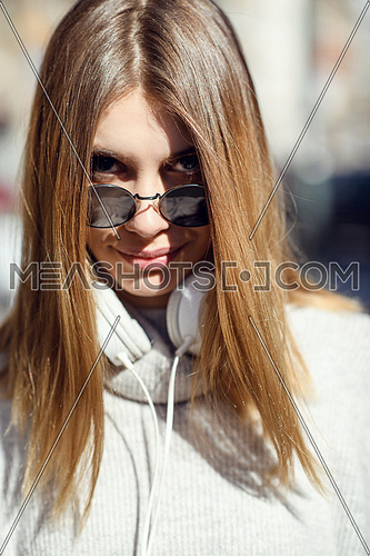 a woman in sunglasses enjoys a walk in the city while listening to music on her headphones