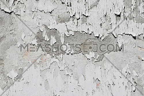 Vintage flakes of old faded white paint over abandoned grey concrete wall