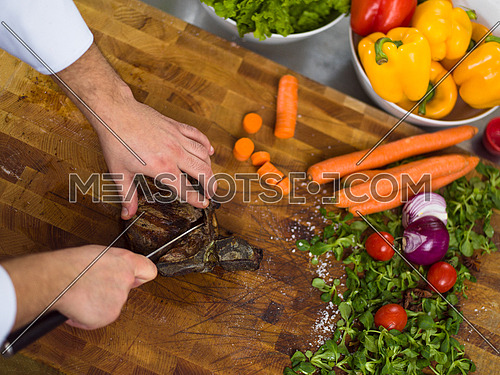closeup of Chef hands in hotel or restaurant kitchen preparing beef steak with vegetable decoration