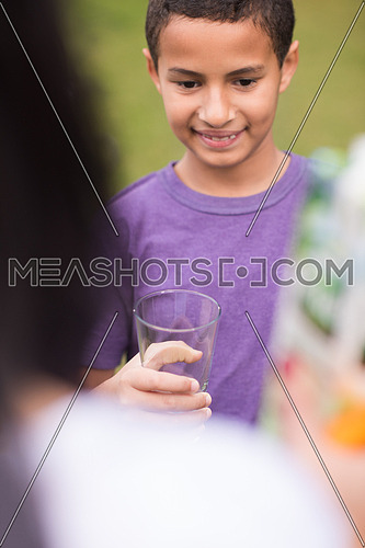 a  middle east boy with a glass hand cheerfully waiting healthy natural beverage outdoors