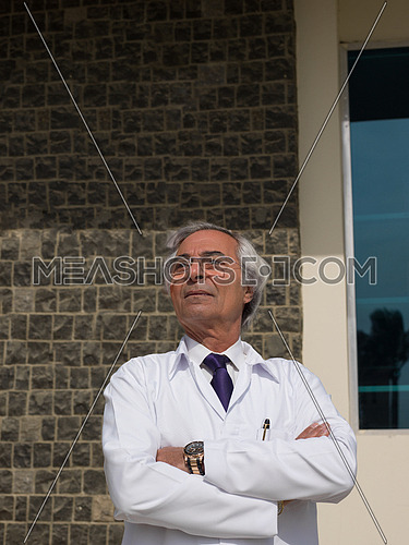 middle eastern senior  doctor portrait in front of modern hospital