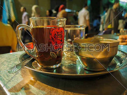 A traditional cup of tea and copper sugar bowl on a metal tray in an oriental street coffee shop
