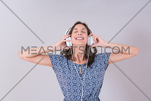 Happy young woman listening and enjoying music with headphones isolated on a white background