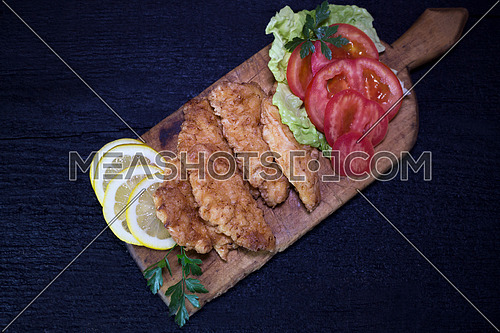 Breaded Chicken Meat With Salad And Lemon Resting On a Rustic Wooden Board