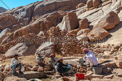 Long shot for a male tourist exploring Sinai Mountain at day. shot for bedouins get water from Ain hudra at Sinai Mountain at day.