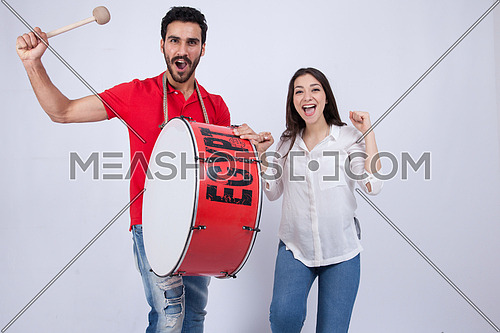 A young man holding big drums and a young woman cheering on a white background