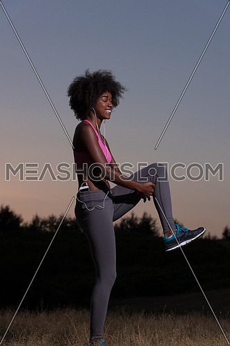 Young healthy black woman is doing stretching exercise relaxing and warm up after jogging and running in the nature beautiful summer evening