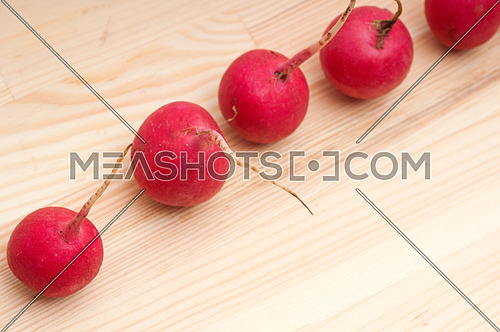 fresh red raw  raddish over pine wood table closeup