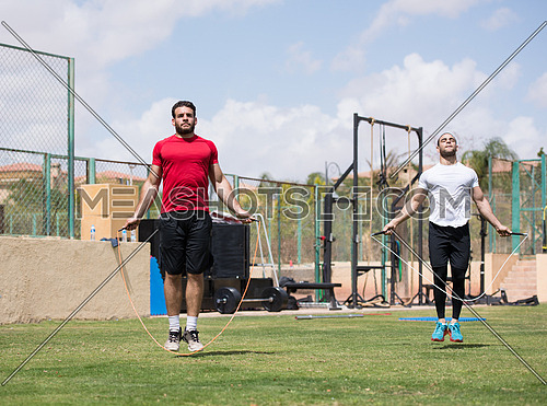 Young middle eastern athletic guys exercise skipping rope outdoors