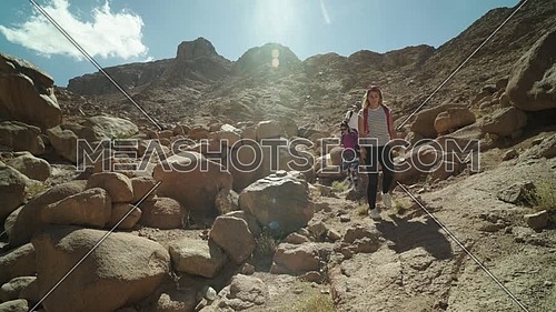 Reveal shot for group of tourists climbing down big rocks explore Sinai Mountain for wadi Freij at day.