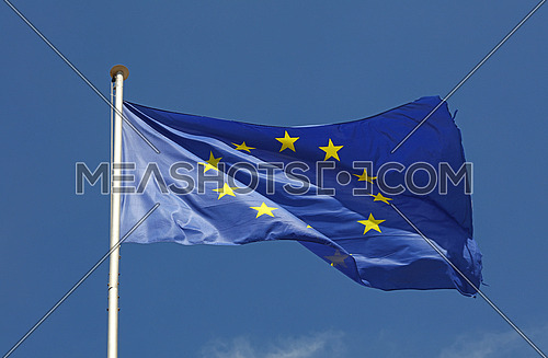 Close up flag of EU, European Union waving and blowing in the wind over blue sky, low angle view