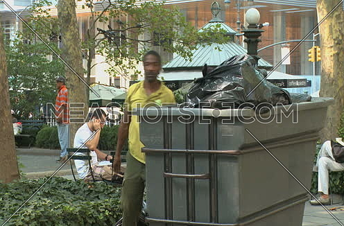 Long shot for African male Park worker disposes of garbage in park at New York City at day