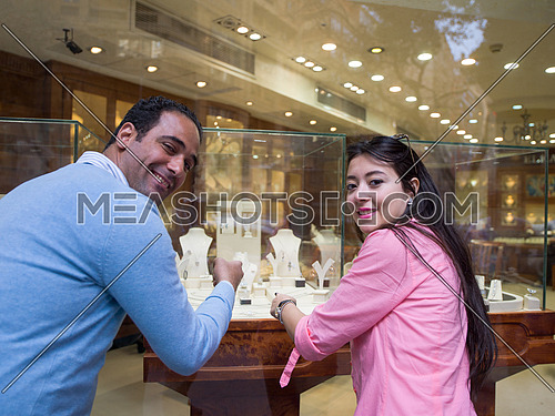 Young middle eastern happy couple enjoying while looking jewelry in the window of a luxury jewelry store