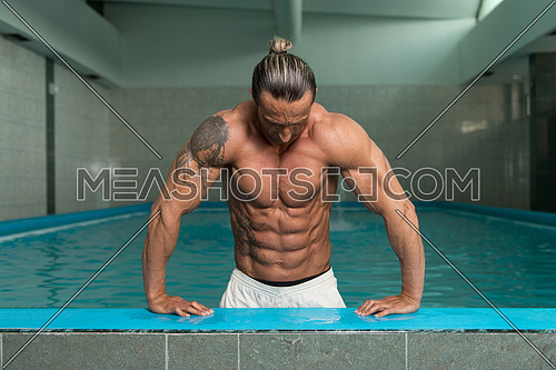 Happy Attractive Muscular Mature Man Resting Relaxed On Edge Of Swimming Pool