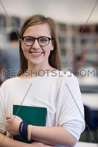 portrait of happy smilling female student girl in school library bholding book