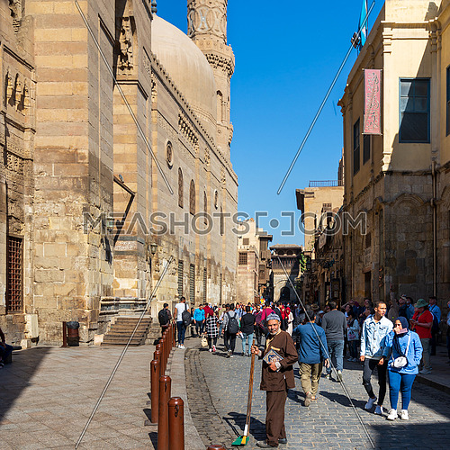 Cairo, Egypt- November 23 2019: Moez Street with local visitors Mosque of Sultan Barquq and Sabil-Kuttab of Katkhuda historic building at the far end, Gamalia district, Old Cairo