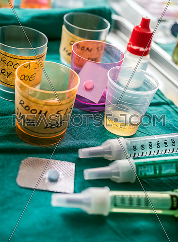 Diverse medication in glasses monodose along with insulin injectors in hospital, conceptual image, vertical composition