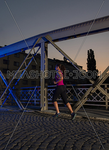 urban sports, young healthy woman jogging across the bridge in the city at early morning in night