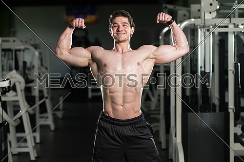 Portrait Of A Young Fit Man Showing Front Double Biceps Pose - Muscular Athletic Bodybuilder Fitness Model Posing