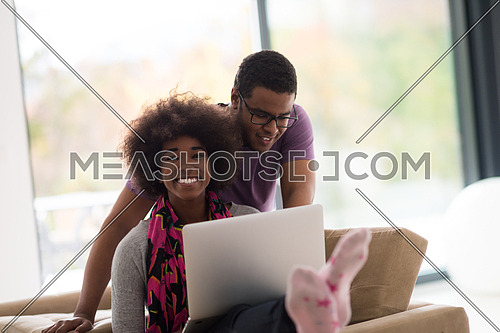 Happy young african american couple shopping online through laptop using credit card at home